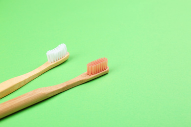 Photo of Natural bamboo toothbrushes on green background. Space for text