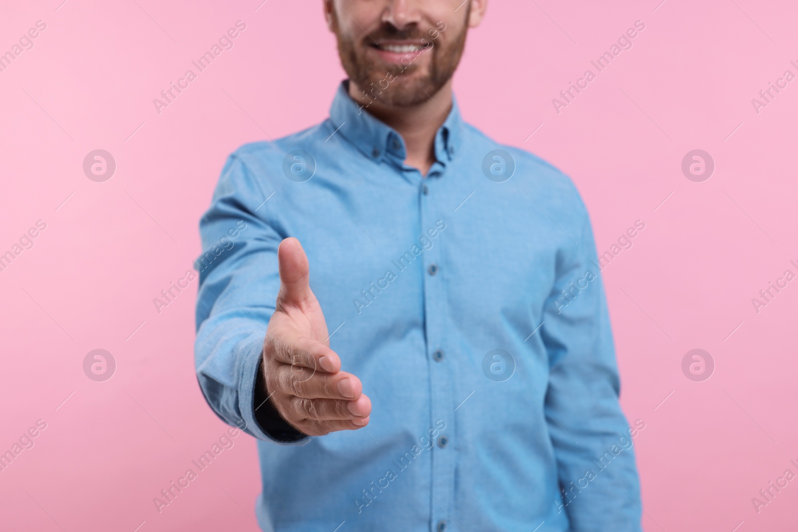 Photo of Man welcoming and offering handshake on pink background, closeup