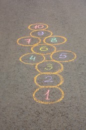 Hopscotch drawn with colorful chalk on asphalt outdoors