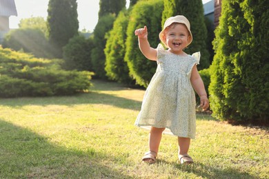 Cute little girl wearing stylish clothes outdoors on sunny day. Space for text