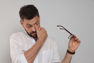 Photo of Man suffering from eyestrain on light background