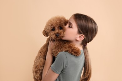 Photo of Little child with cute puppy on beige background. Lovely pet