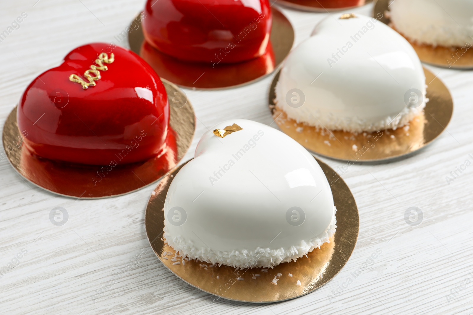 Photo of St. Valentine's Day. Delicious heart shaped cakes on white wooden table, closeup