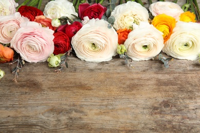 Photo of Beautiful ranunculus flowers and space for text on wooden background