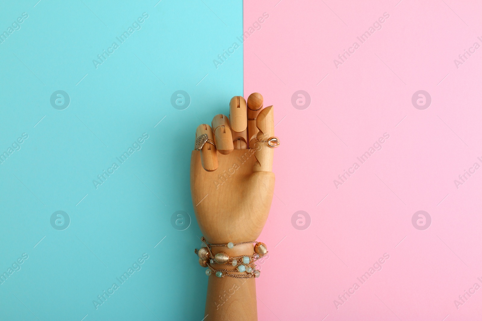 Photo of Decorative arm with stylish jewelry on color background, top view