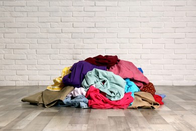Pile of dirty clothes on floor near brick wall