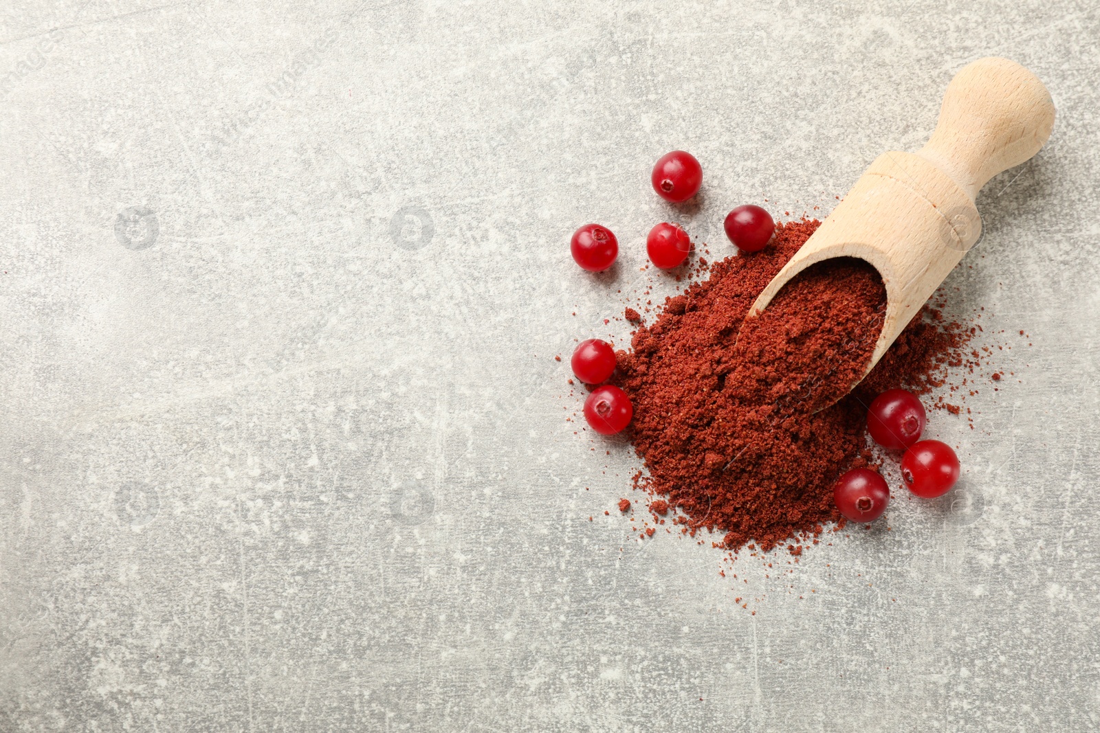 Photo of Cranberry powder, scoop and fresh berries on light grey table, top view. Space for text