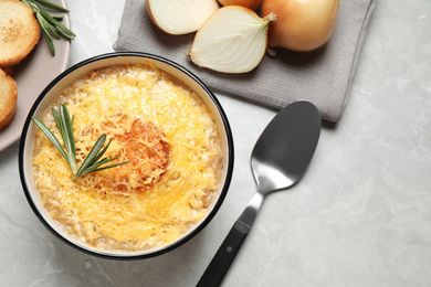 Photo of Tasty homemade french onion soup served on grey marble table, flat lay