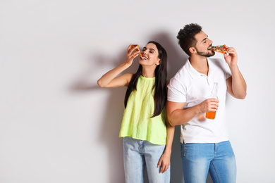 Happy couple with pizza and beer on white background, space for text