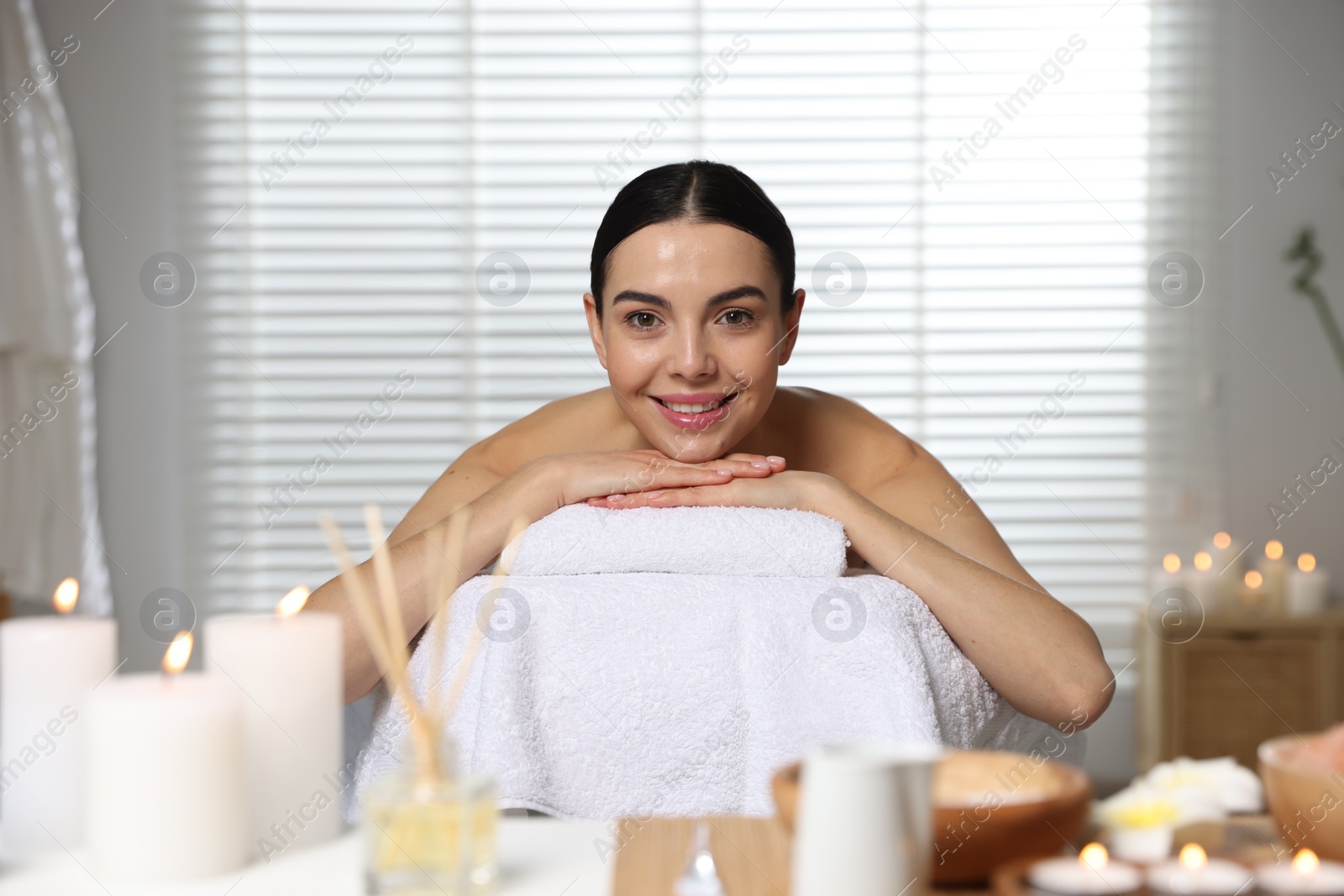 Photo of Beautiful happy woman relaxing on massage table in spa salon