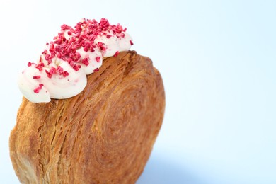 Photo of One supreme croissant with cream on light blue background, closeup with space for text. Tasty puff pastry