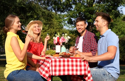 Group of people having picnic at table in park on summer day