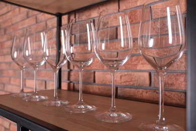 Empty wine glasses on shelf near brick wall