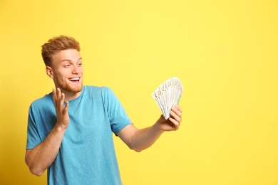 Photo of Portrait of excited lottery winner with money on yellow background
