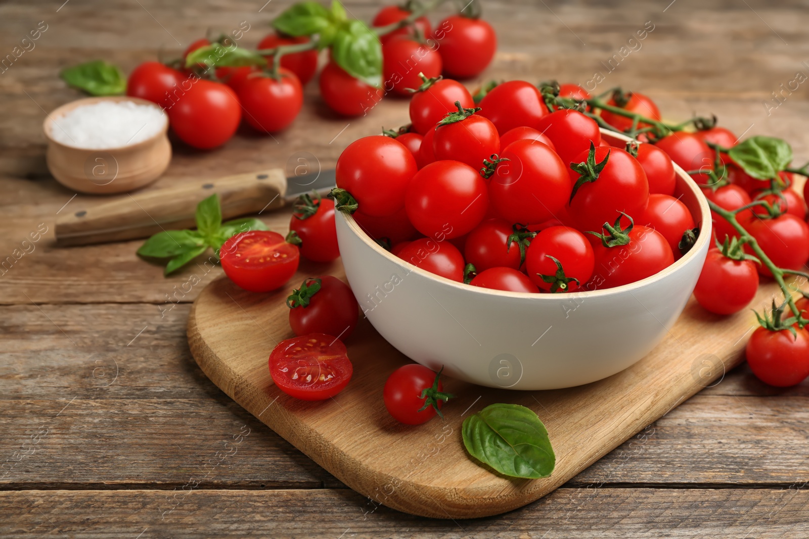 Photo of Fresh ripe cherry tomatoes and basil on wooden table