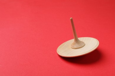 One wooden spinning top on red background, closeup. Space for text