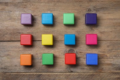 Photo of Blank colorful cubes on wooden table, flat lay
