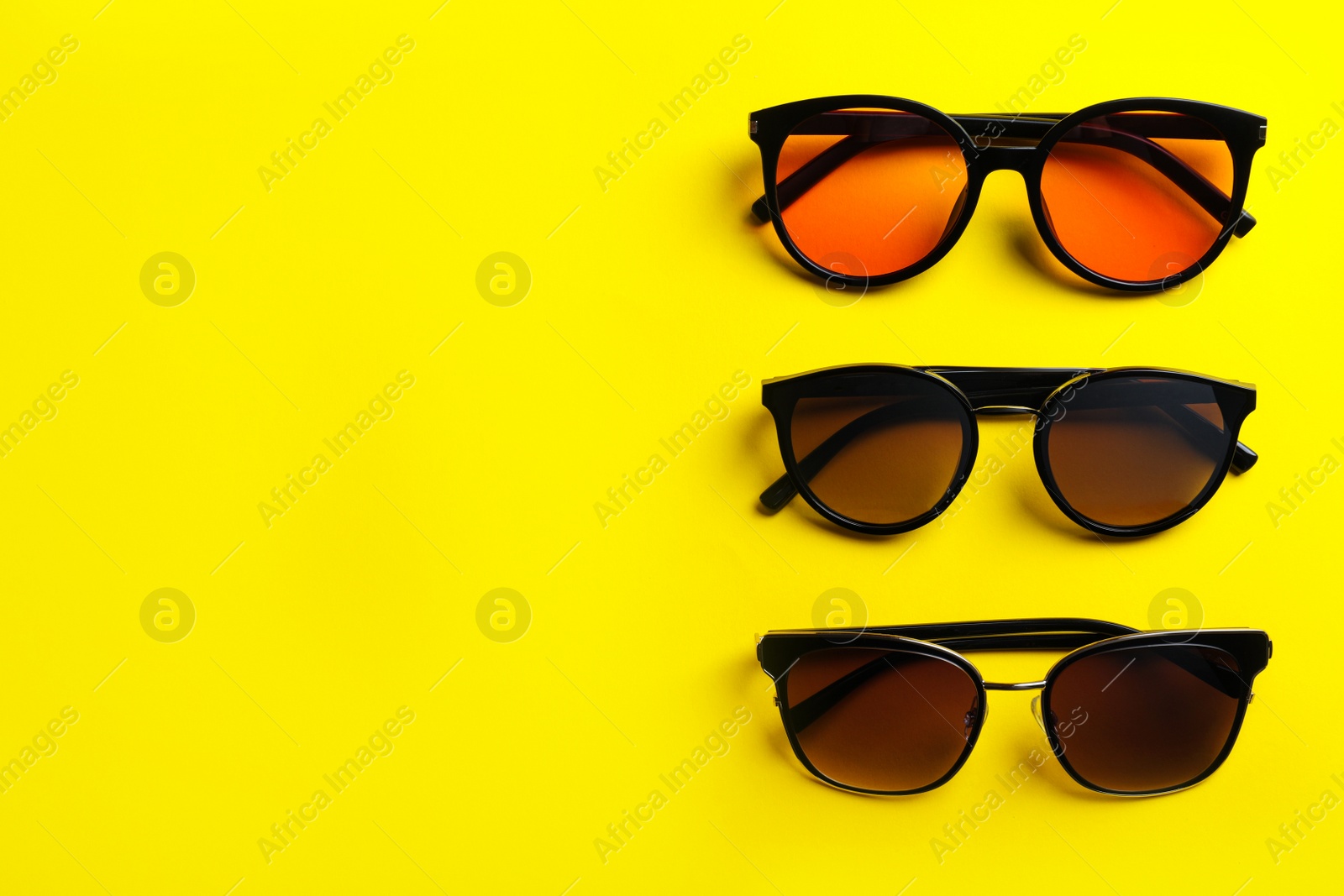 Photo of Many stylish sunglasses on yellow background, flat lay. Space for text