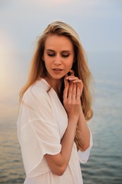 Photo of Beautiful young woman near sea in evening