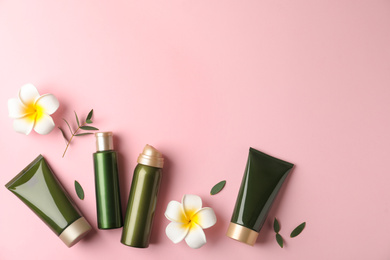 Photo of Flat lay composition with cosmetic products and tropical flowers on pink background. Space for text