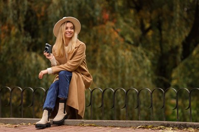 Happy woman with camera in autumn park. Space for text