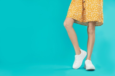 Photo of Woman in stylish sport shoes on light blue background. Space for text