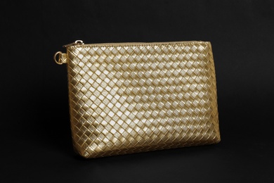 Photo of Elegant gold cosmetic bag on black background