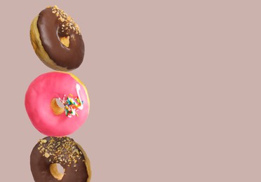 Image of Different tasty donuts on pinkish grey background, space for text