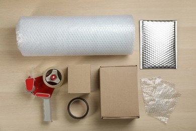 Photo of Flat lay composition with bubble wrap roll on wooden background