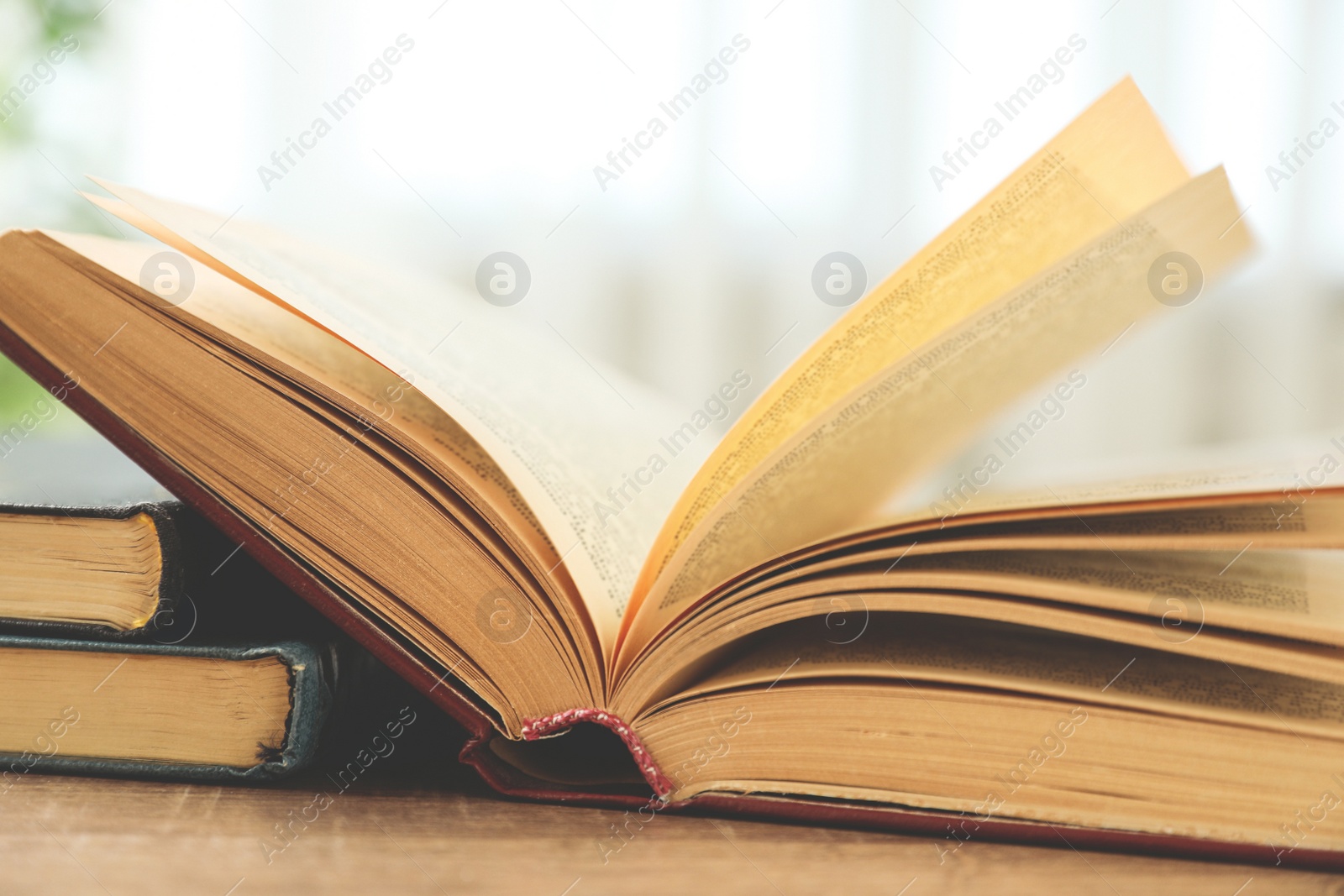 Photo of Open hardcover book on wooden table indoors, closeup