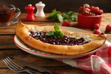 Photo of Delicious sweet cottage cheese pastry with cherry jam on wooden table