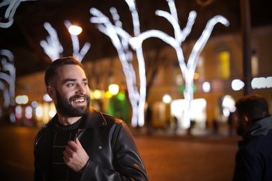 Handsome young man spending time in city at night