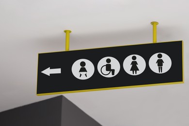 Public toilet sign with symbols and arrow showing direction