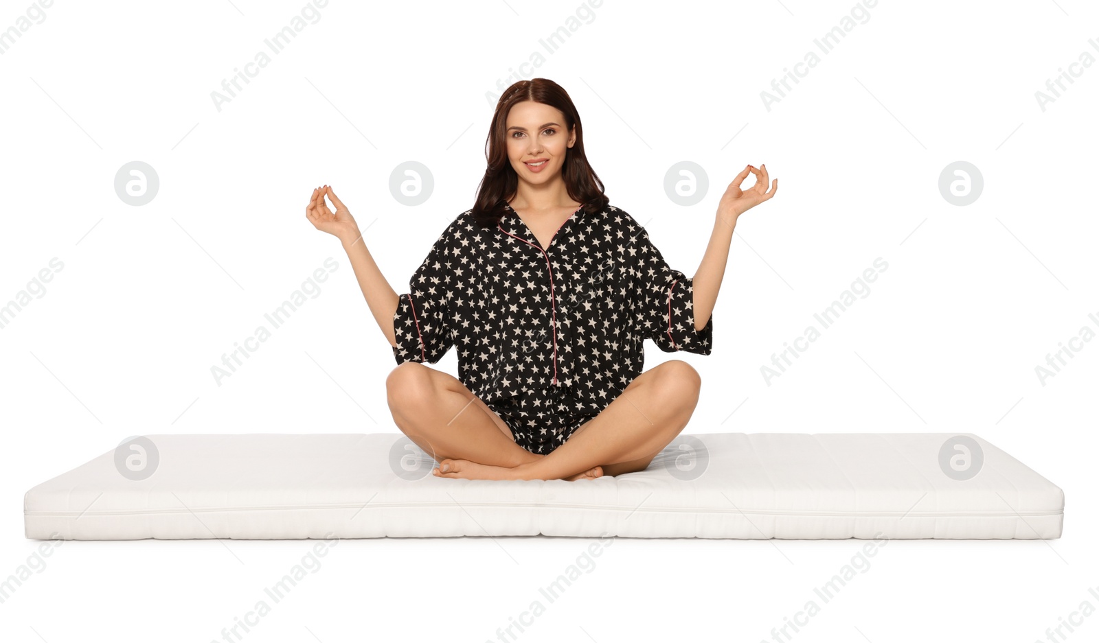 Photo of Young woman meditating on soft mattress against white background