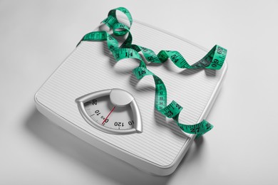 Photo of Weight loss concept. Scales and measuring tape on white background