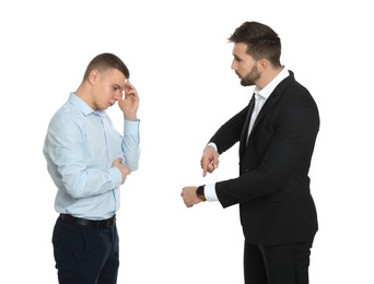 Businessman pointing on wrist watch while scolding employee for being late against white background