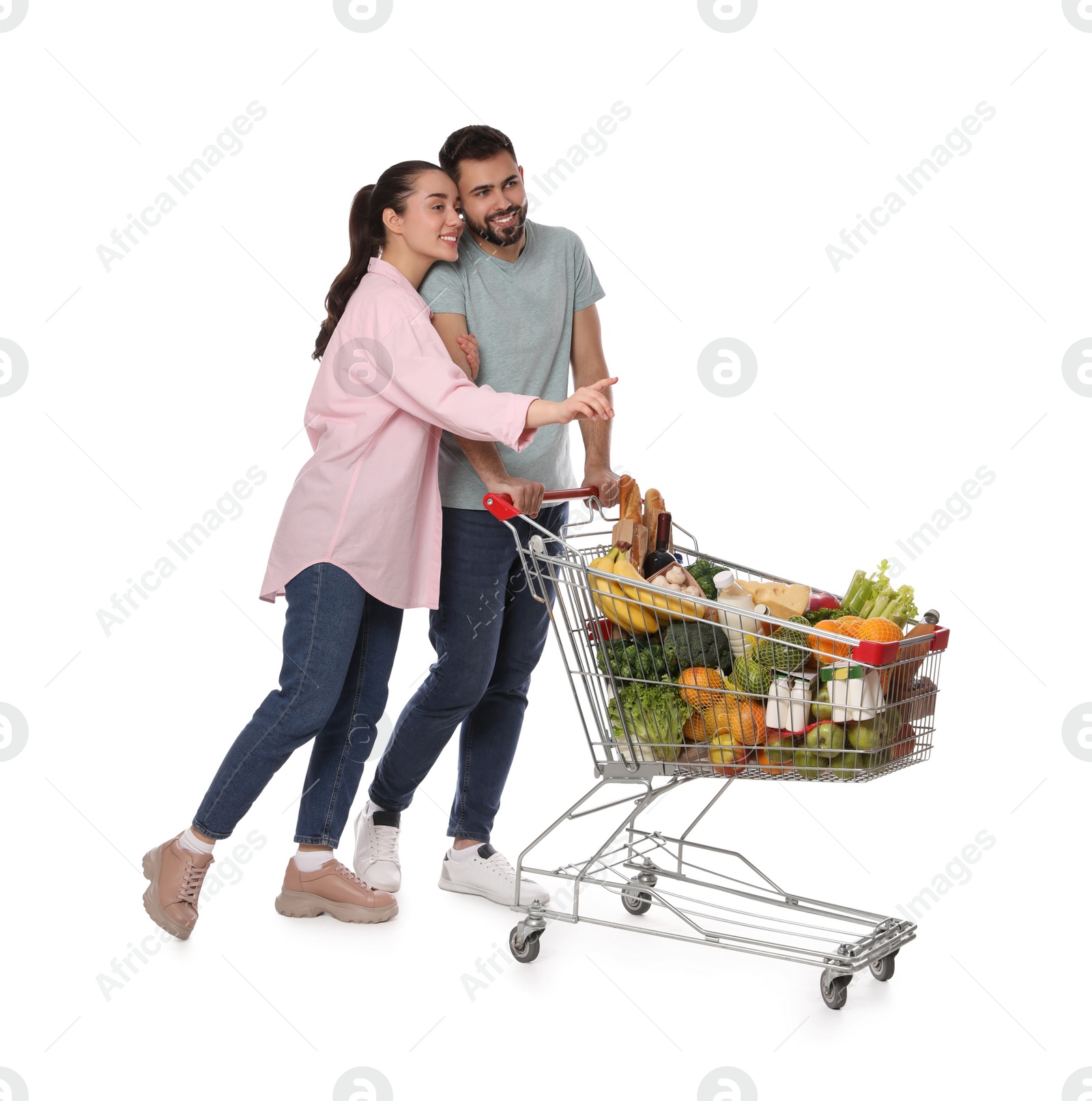 Photo of Happy couple with shopping cart full of groceries on white background