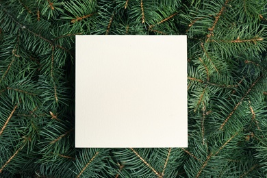 Blank card on Christmas tree branches as background, top view. Space for text