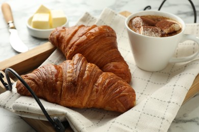 Photo of Tasty croissants served with cup of hot drink on white marble table, closeup