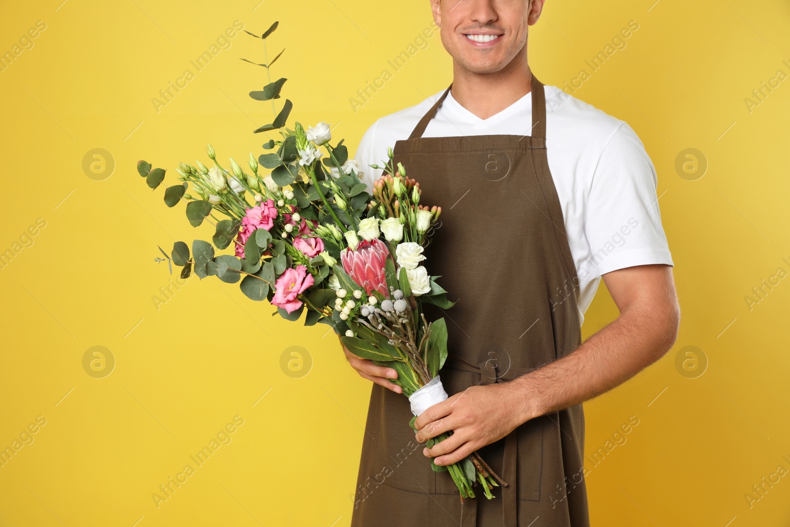 Photo of Florist with beautiful bouquet on yellow background, closeup