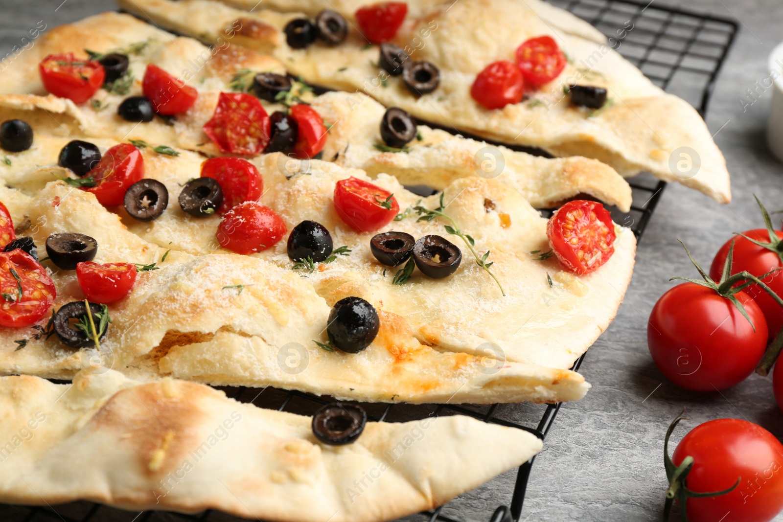 Photo of Delicious focaccia bread with olives and tomatoes on grey table, closeup