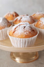 Cake stand with tasty muffins on light grey table, closeup