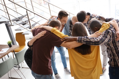 Photo of People standing together in circle indoors. Unity concept