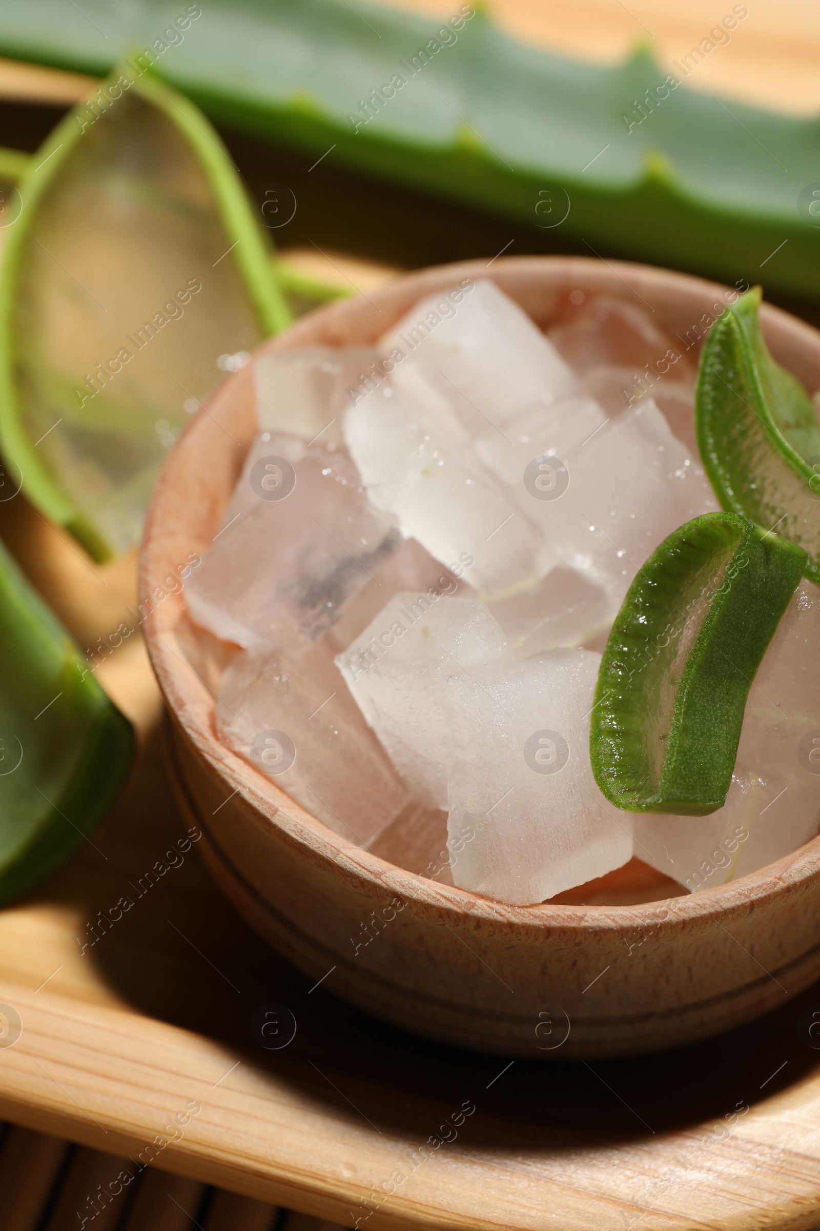 Photo of Aloe vera gel and slices of plant on table, closeup