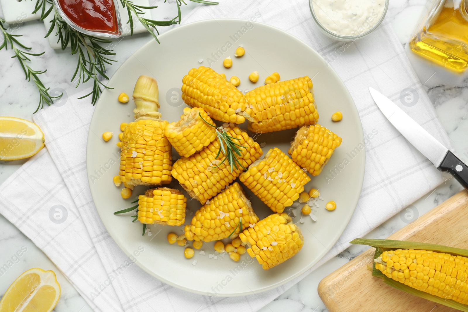 Photo of Plate with tasty cooked corn cobs on white marble table, flat lay