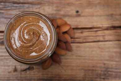 Tasty almond nut paste in jar on wooden table, top view. Space for text