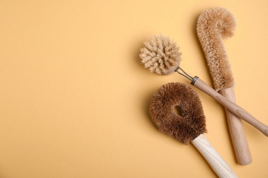 Photo of Cleaning brushes on orange background, flat lay with space for text. Dish washing supplies