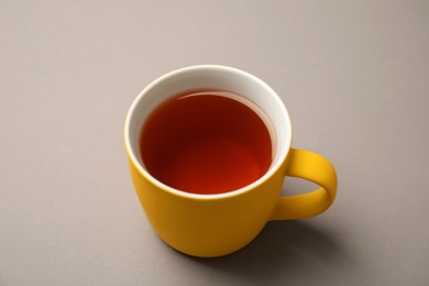 Photo of Cup of black tea on color background