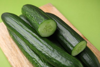 Photo of Many fresh cucumbers on green background, closeup