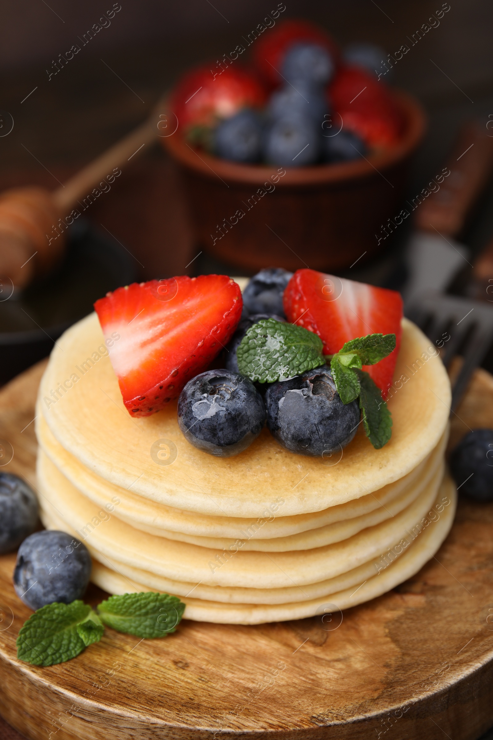 Photo of Delicious pancakes with strawberries, blueberries and mint on table, closeup